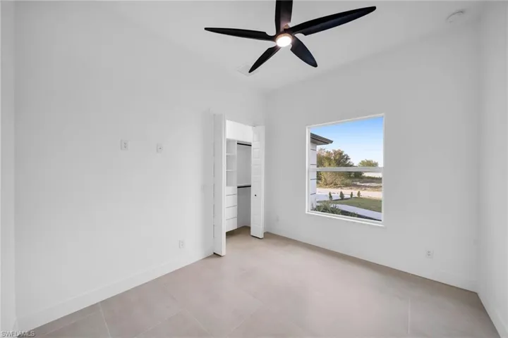 Unfurnished bedroom featuring light tile patterned floors, a closet, a ceiling fan, and baseboards