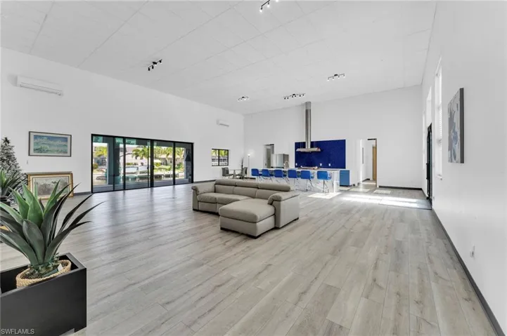 Living room featuring light wood-style flooring, a high ceiling, and a wall mounted AC