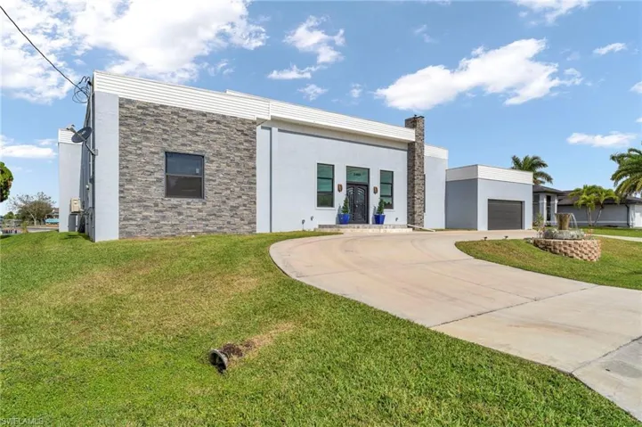 Contemporary home with concrete driveway, a front yard, stucco siding, stone siding, and a chimney