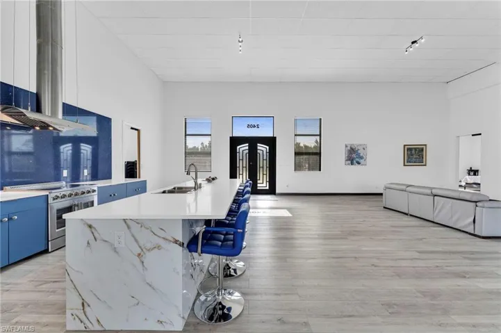 Kitchen featuring a kitchen bar, range hood, high end stainless steel range oven, open floor plan, and a high ceiling