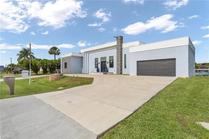 Contemporary home featuring a front yard, driveway, stucco siding, and an attached garage
