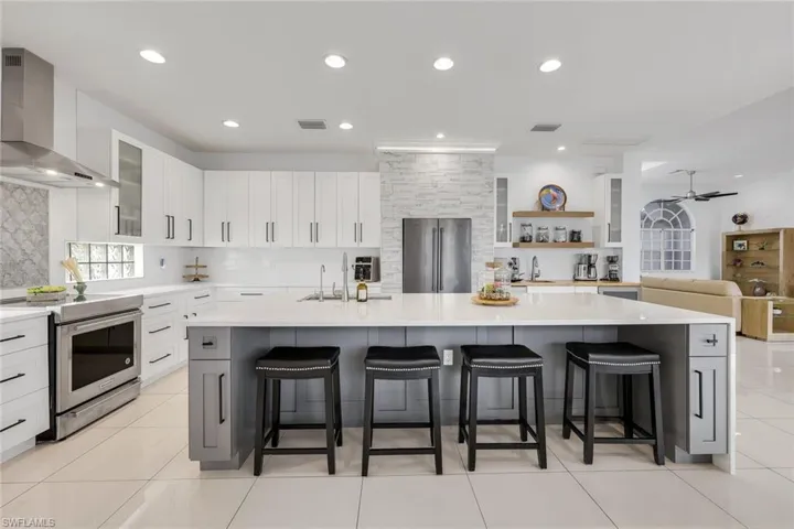Modern kitchen featuring white cabinetry, a large center island with seating, stainless steel appliances, and tile flooring