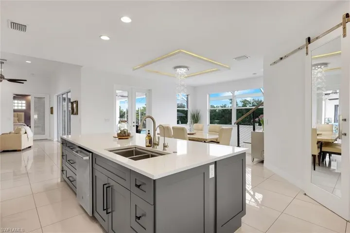 Modern kitchen island with a double basin sink, stainless steel dishwasher, and light-toned countertop