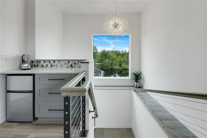 Built-in wet bar with gray cabinetry, decorative tile backsplash, and a light-toned countertop