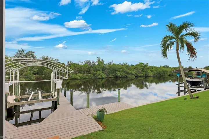 Waterfront property featuring a boat lift, dock, and manicured lawn