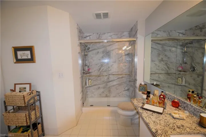 Full bath with toilet, vanity, tile patterned flooring, and a marble finish shower