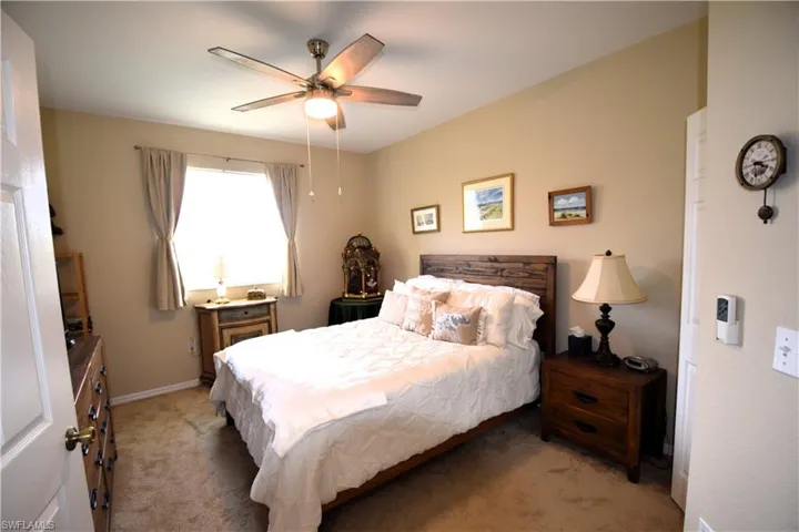Bedroom with light carpet, ceiling fan, and baseboards