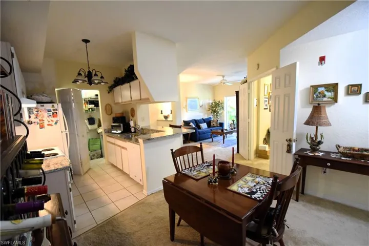 Dining space featuring a chandelier, light carpet, ceiling fan, and light tile patterned flooring