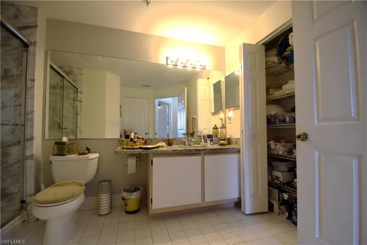 Bathroom featuring a stall shower, vanity, toilet, and tile patterned flooring