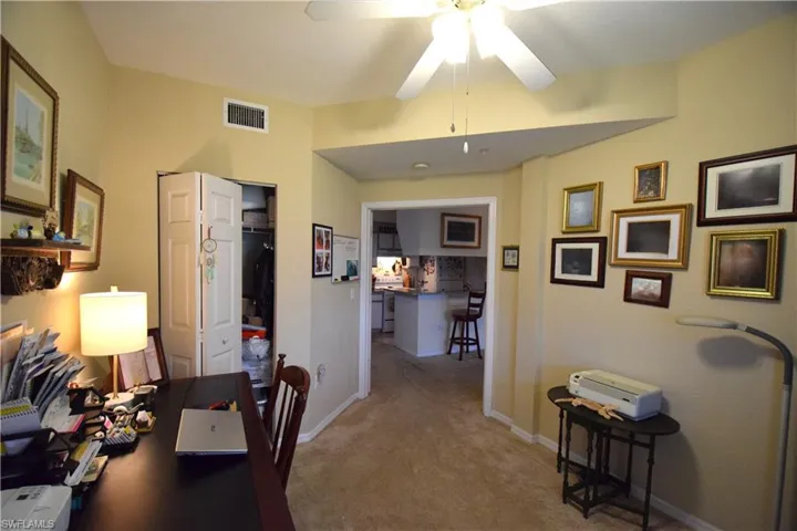 Carpeted office space with a ceiling fan and baseboards