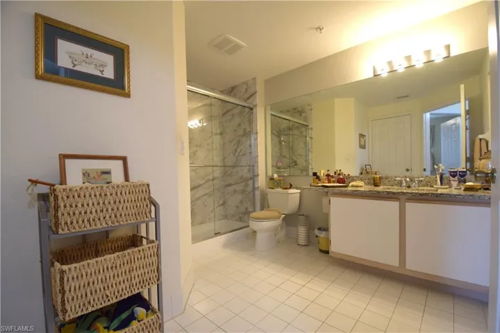Full bath featuring toilet, vanity, a stall shower, and tile patterned floors