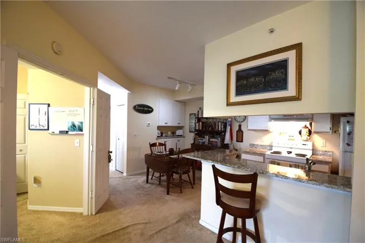 Kitchen featuring extractor fan, light carpet, white electric range oven, and stone counters