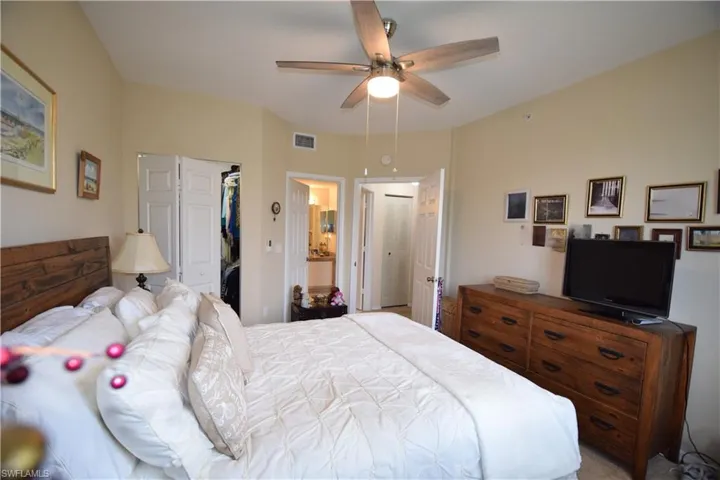 Bedroom with a spacious closet, a closet, a ceiling fan, and ensuite bath
