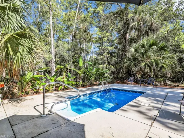 Swimming pool featuring a patio area and view of scattered trees