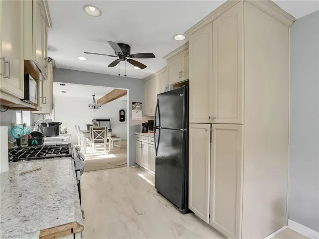 Kitchen with freestanding refrigerator, cream cabinetry, recessed lighting, hanging light fixtures, and a chandelier