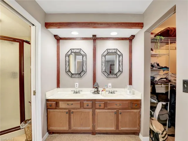 Bathroom featuring double vanity, a stall shower, and a spacious closet