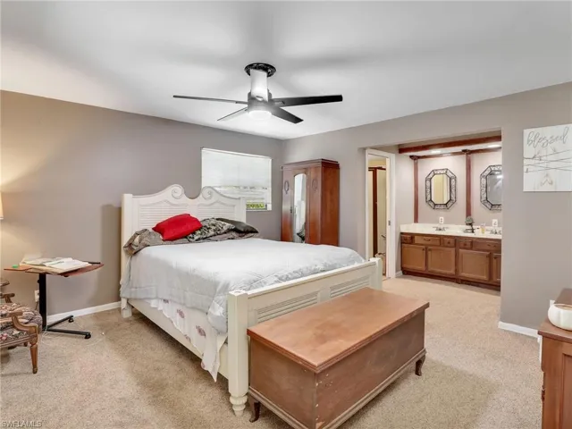 Bedroom with light colored carpet, a ceiling fan, and connected bathroom