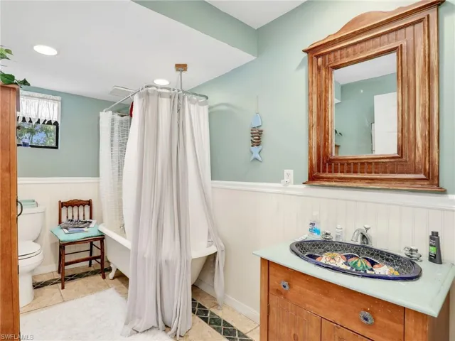 Full bathroom featuring vanity, a wainscoted wall, a combined bath / shower with freestanding tub, recessed lighting, and light tile patterned flooring