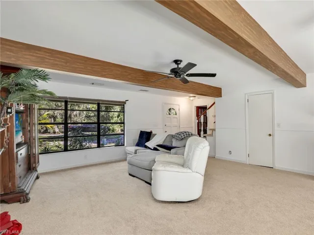 Living area with beamed ceiling, light colored carpet, and a ceiling fan
