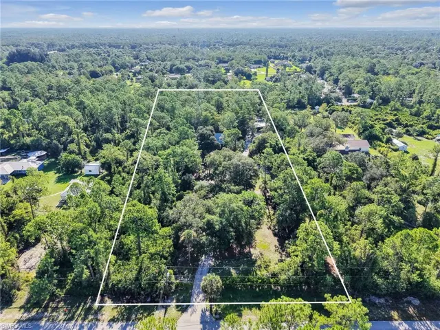 Aerial view of property and surrounding area with property parcel outlined and a forest
