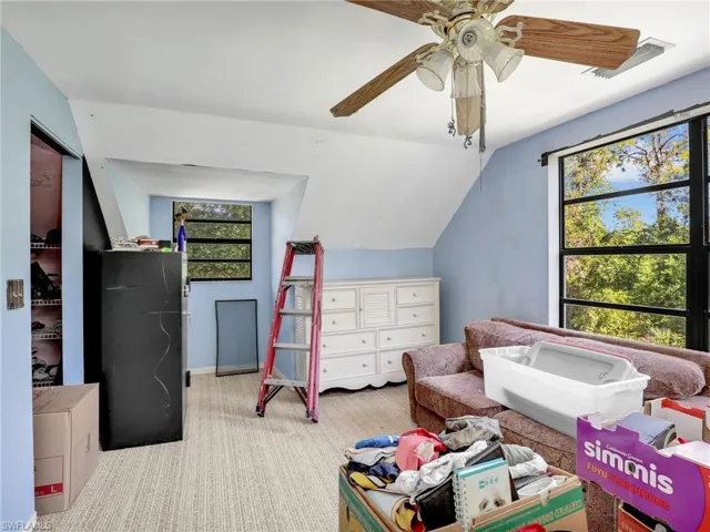 Carpeted bedroom featuring vaulted ceiling and a ceiling fan
