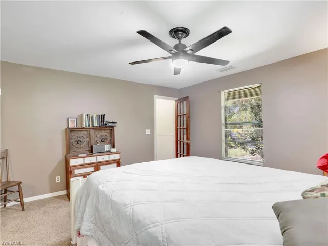 Carpeted bedroom with a ceiling fan and baseboards