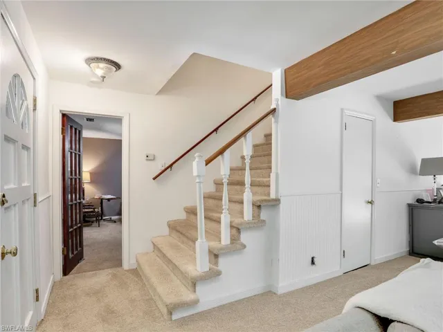 Stairway featuring carpet flooring and a wainscoted wall