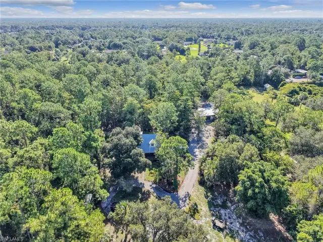 Aerial view of property and surrounding area with a forest