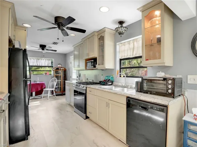 Kitchen featuring cream cabinets, black appliances, healthy amount of natural light, and recessed lighting
