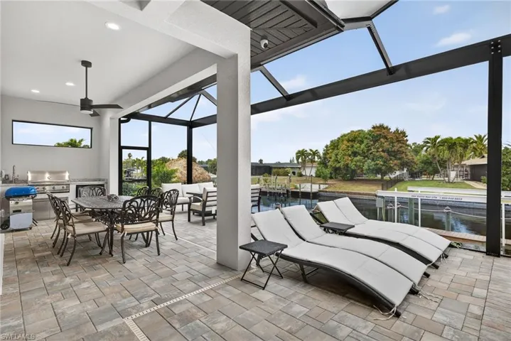 View of patio / terrace with a lanai, a sunroom, area for grilling, outdoor dining area, and a ceiling fan