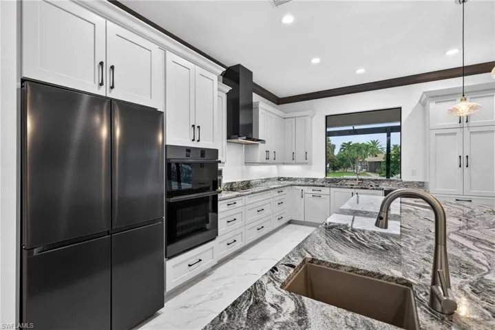 Kitchen featuring black appliances, light stone countertops, light marble finish floors, white cabinets, and recessed lighting