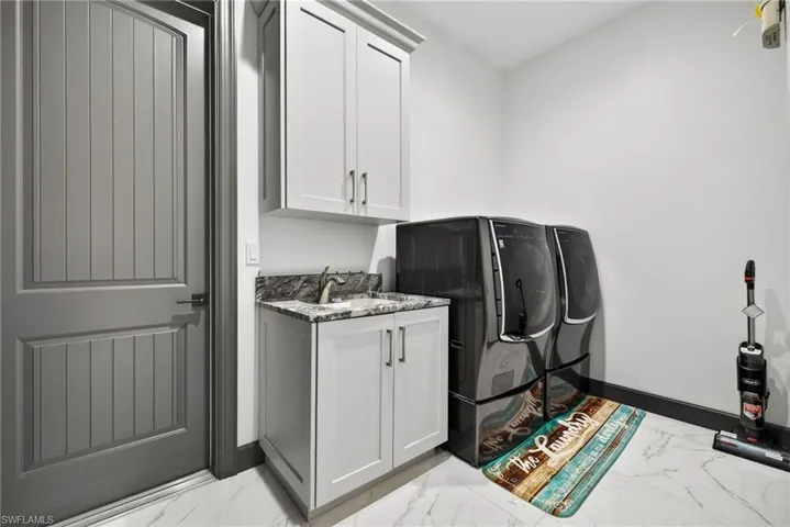 Laundry area with cabinet space, washing machine and clothes dryer, and light marble finish flooring