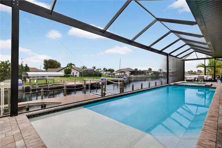 View of pool with a sunroom, boat lift, a water view, a boat dock, and a pool with connected hot tub
