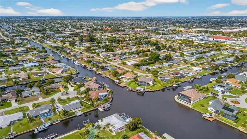 Aerial view of property and surrounding area featuring nearby suburban area and a nearby body of water