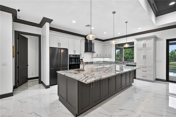Kitchen featuring appliances with stainless steel finishes, light stone counters, white cabinets, a spacious island, and recessed lighting