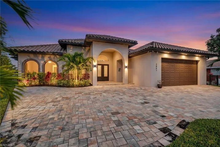 Mediterranean / spanish home featuring stucco siding, a garage, decorative driveway, a tile roof, and french doors