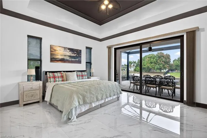 Bedroom featuring light marble finish flooring, access to outside, a ceiling fan, ornamental molding, and a sunroom