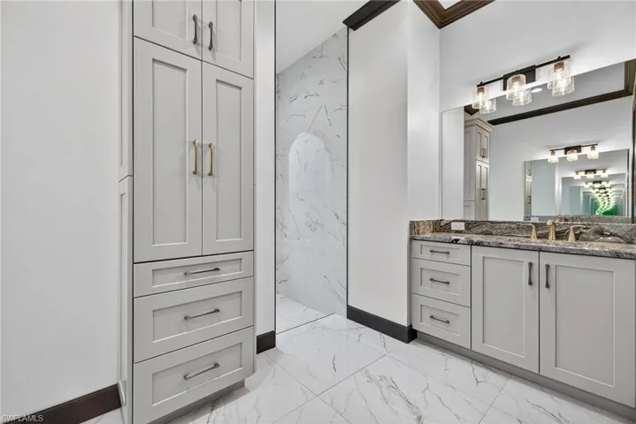 Bathroom with light marble finish floors, vanity, and a marble finish shower