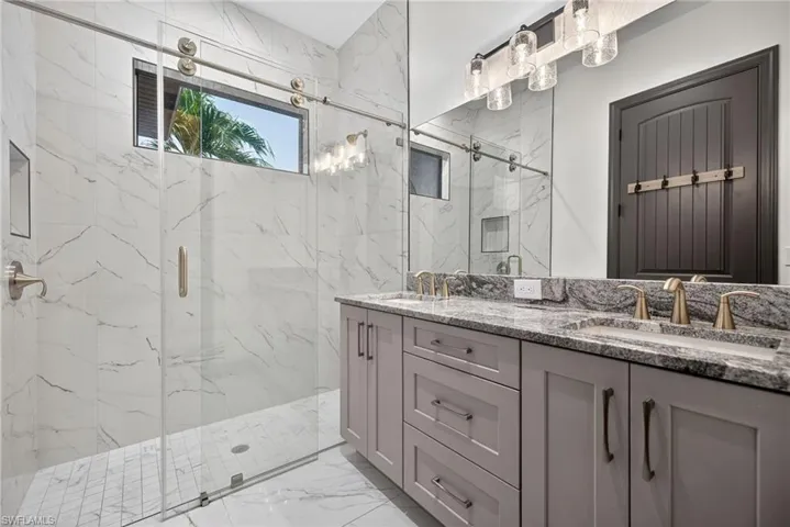 Bathroom with a marble finish shower and double vanity