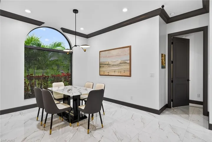Dining space with light marble finish flooring, ornamental molding, recessed lighting, and a chandelier