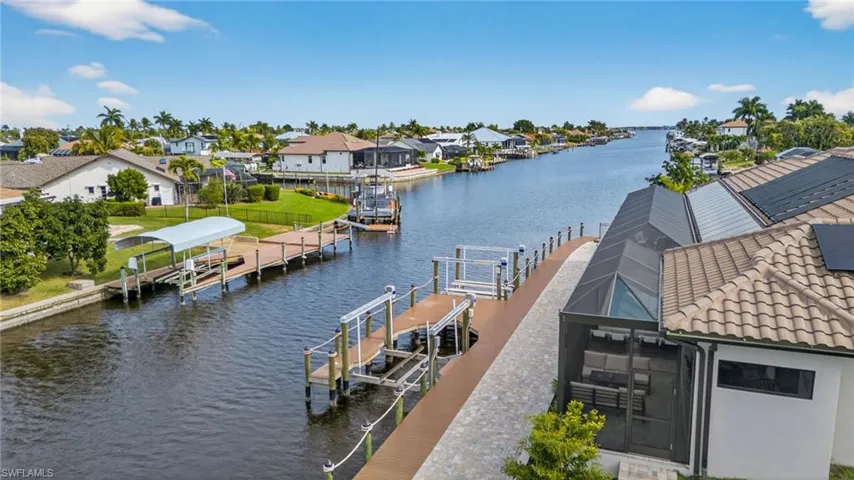Dock with boat lift, a water view, a residential view, and glass enclosure