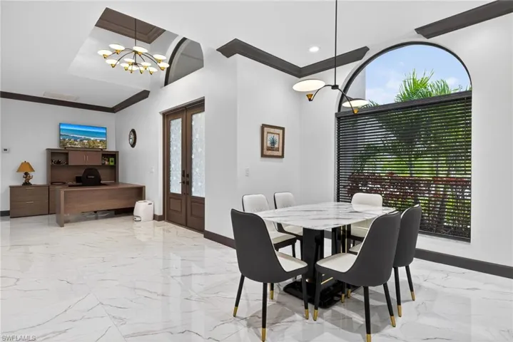 Dining area featuring french doors, a chandelier, an office area, ornamental molding, and light marble finish flooring