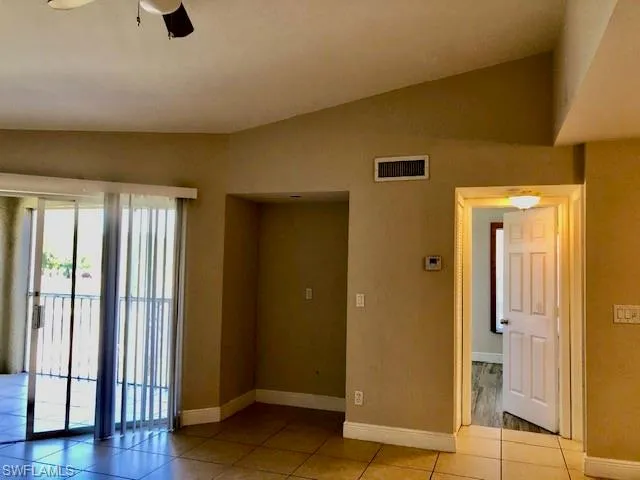 Unfurnished room with lofted ceiling, a ceiling fan, and light tile patterned floors