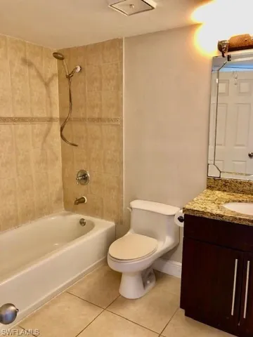 Bathroom with vanity, tub / shower combination, and light tile patterned floors