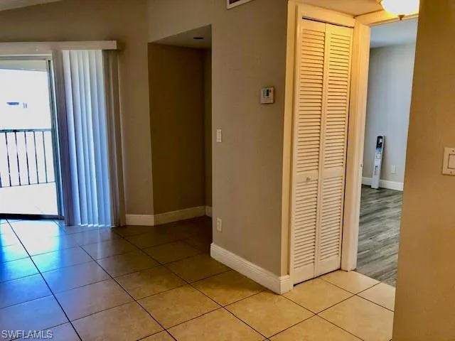 Hall with light tile patterned flooring and baseboards