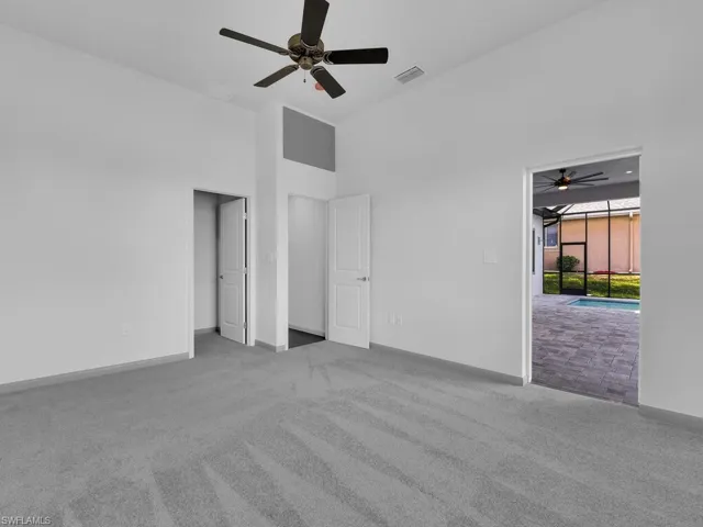 Unfurnished bedroom featuring visible vents, carpet floors, a towering ceiling, and access to outside