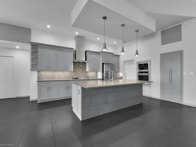 Kitchen with open shelves, wall chimney range hood, tasteful backsplash, stainless steel appliances, and light countertops