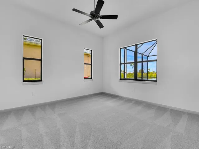 Carpeted empty room featuring baseboards and ceiling fan