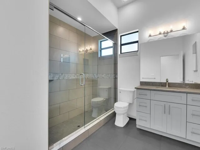 Bathroom with tile patterned floors, vanity, toilet, and a shower stall