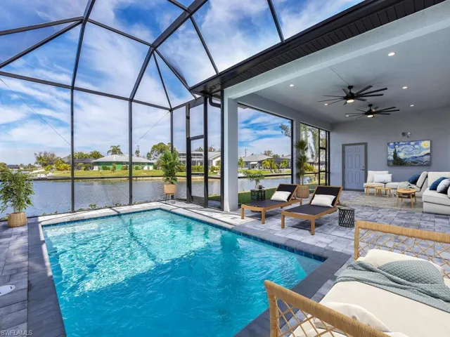 Pool with an outdoor living space, ceiling fan, a water view, glass enclosure, and a patio area